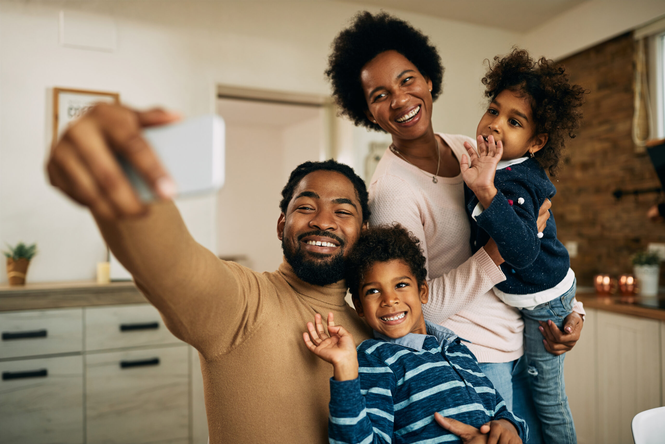 Happy black parents with kids making video call over smart phone