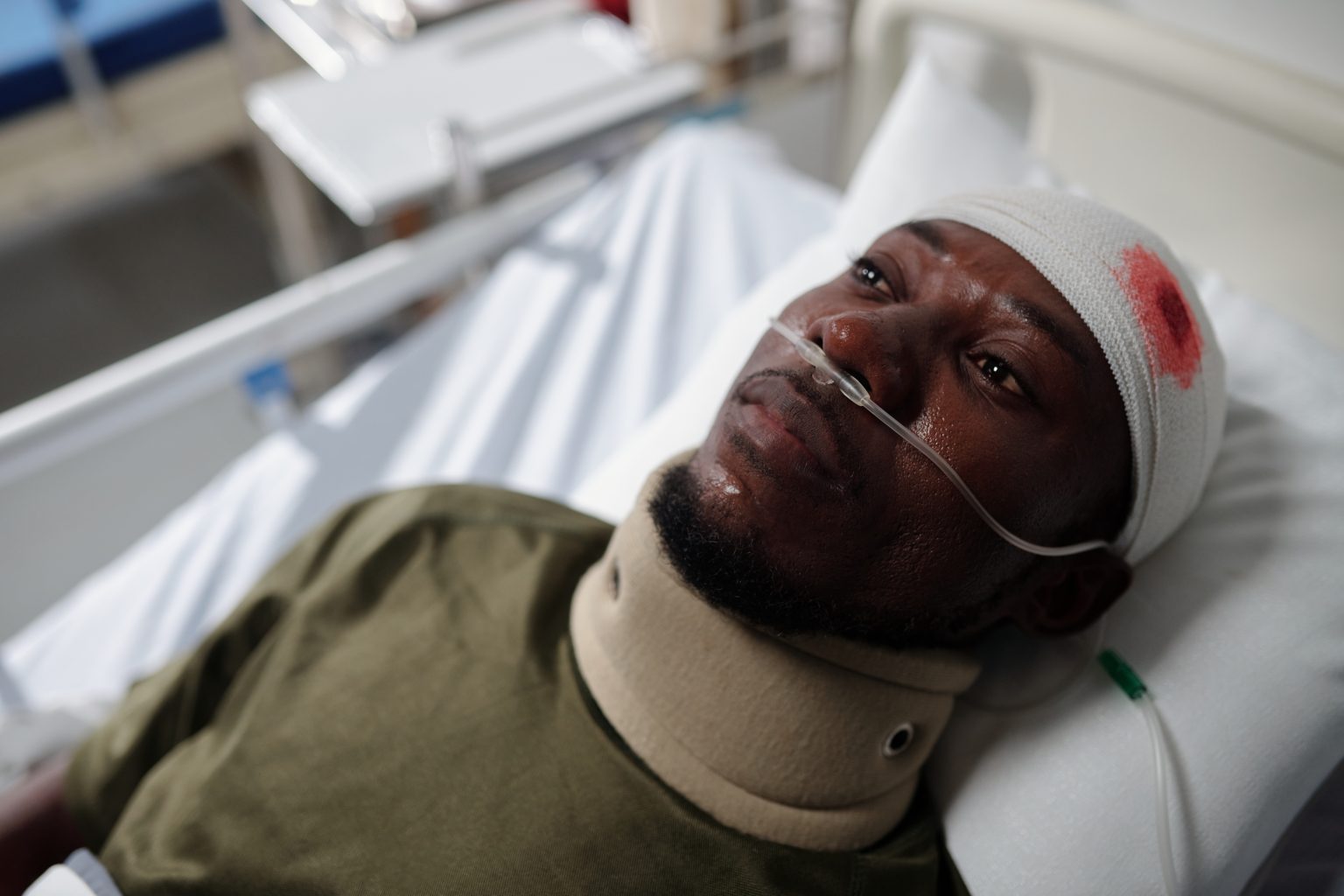 Injured man with bleeding head injury lying on bed in hospital